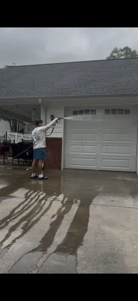 Pressure washing in progress outside a garage