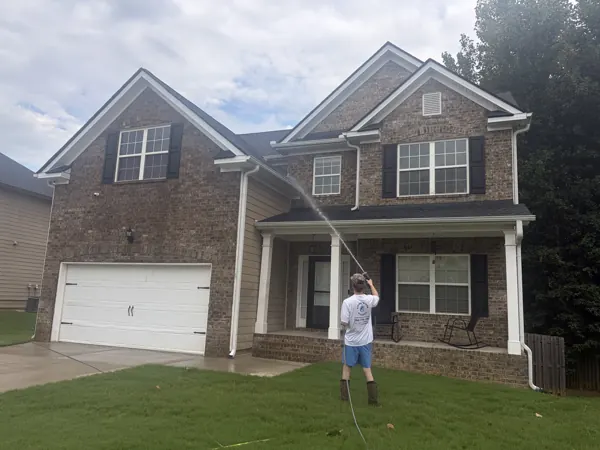 House washing in progress outside a two-story brick home