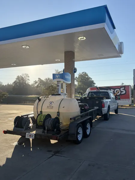 Pressure washing truck and equipment trailer at a fuel station