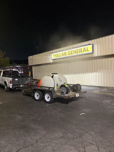 Pressure washing truck and trailer outside a commercial building at night